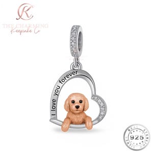 May include: A silver charm with a heart-shaped pendant featuring a small, tan-coloured dog. The heart is inscribed with "I love you forever" and accented with clear crystals. The charm has a loop for attachment.
