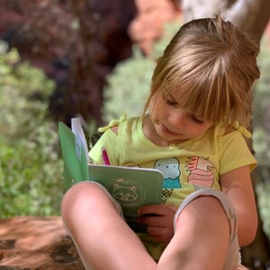 Peut inclure: Une jeune personne est assise &agrave; l'ext&eacute;rieur, en train d'&eacute;crire dans un journal vert avec un crayon rose. Le journal a une illustration de raton laveur sur la couverture et le texte "Nature's Diary".