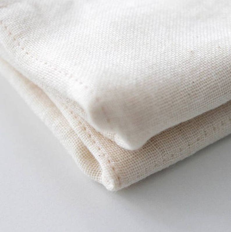 May include: A close-up of a folded white cotton fabric. The fabric is soft and has a slightly textured surface.