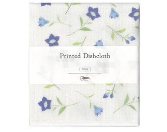Könnte beinhalten: Gefaltetes weißes Geschirrtuch mit einem floralen Muster aus blauen Blumen und grünen Stielen. Das Geschirrtuch ist mit einem weißen Band umwickelt, auf dem "Printed Dishcloth" steht. Der Markenname "Hawrap" ist ebenfalls sichtbar.