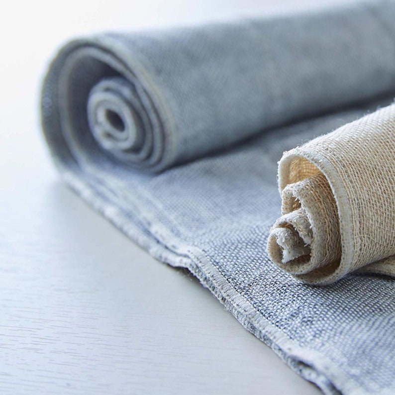 May include: Two rolled up towels, one is a light blue waffle weave and the other is a natural linen weave.