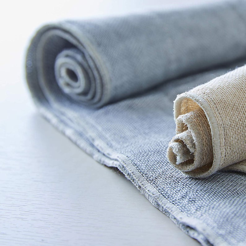 May include: Two rolled up fabric towels, one is a light blue color and the other is a light beige color.