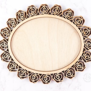 May include: A wooden oval frame with a decorative rose design. The frame is made of light brown wood and has a natural finish.