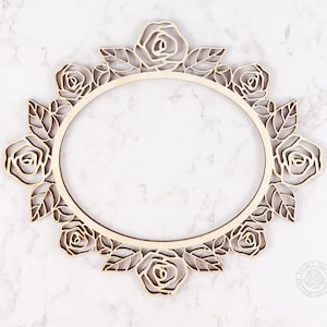 May include: A wooden oval frame with a delicate floral design. The frame is made of natural wood and features a repeating pattern of roses and leaves.