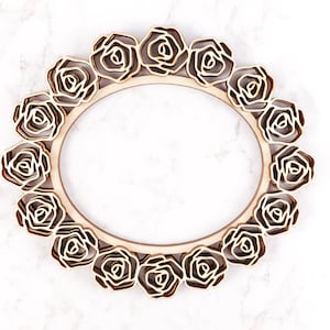 May include: A wooden frame with a decorative design of roses around the perimeter. The frame is light brown and has a natural wood finish.