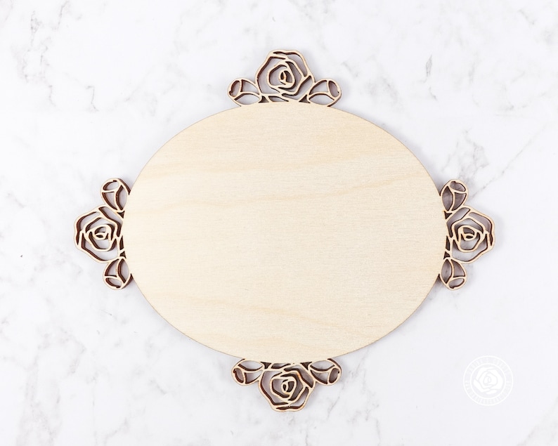 May include: A round wooden plaque with a decorative floral design around the edge. The plaque is blank and ready to be personalized.