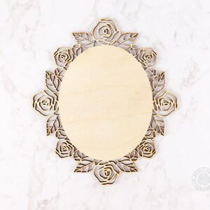 May include: A wooden oval-shaped plaque with a decorative rose design around the edge. The plaque is blank and ready to be personalized.