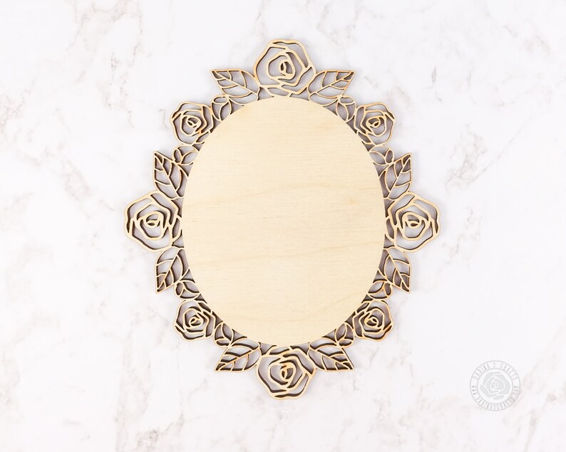 May include: A wooden oval-shaped plaque with a decorative rose design around the edge. The plaque is blank and ready to be personalized.
