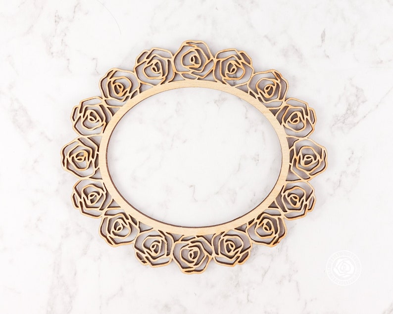 May include: A wooden frame with a circular design of roses. The frame is made of light brown wood and has a smooth finish.