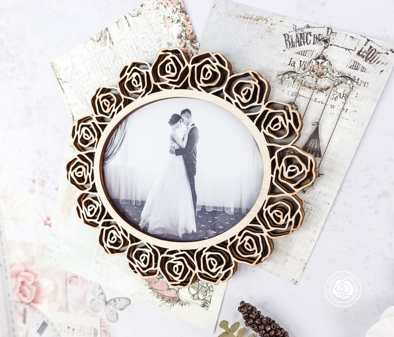 May include: A wooden picture frame with a decorative rose design. The frame is holding a black and white photo of a couple.