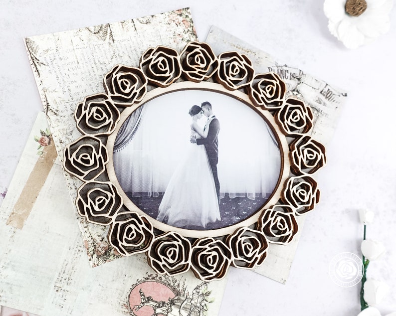 May include: A wooden picture frame with a decorative design of roses surrounding a photo of a couple. The photo shows a bride and groom embracing.