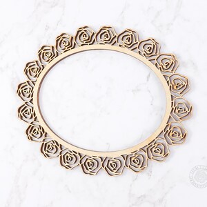 May include: A wooden round frame with a decorative rose design. The frame is made of natural wood and has a smooth finish.
