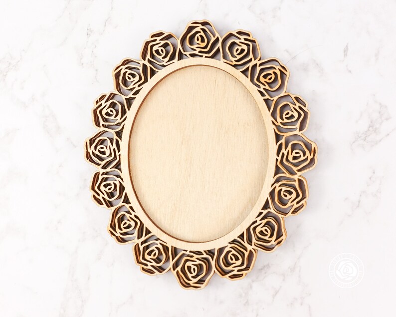 May include: A wooden oval frame with a decorative rose design. The frame is made of light brown wood and has a smooth finish.