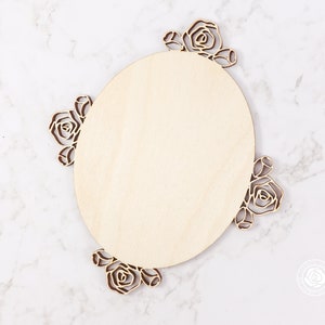 May include: A round wooden sign with a floral design. The sign is made of unfinished wood and has a natural wood grain. The floral design is cut out of the wood and is in the shape of roses.