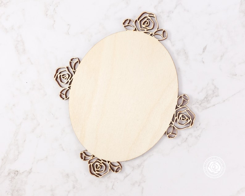 May include: A round wooden sign with a floral design. The sign is made of unfinished wood and has a natural wood grain. The floral design is cut out of the wood and is in the shape of roses.