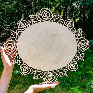 May include: A wooden round sign with a decorative floral border of roses and leaves. The sign is blank and ready to be personalized.