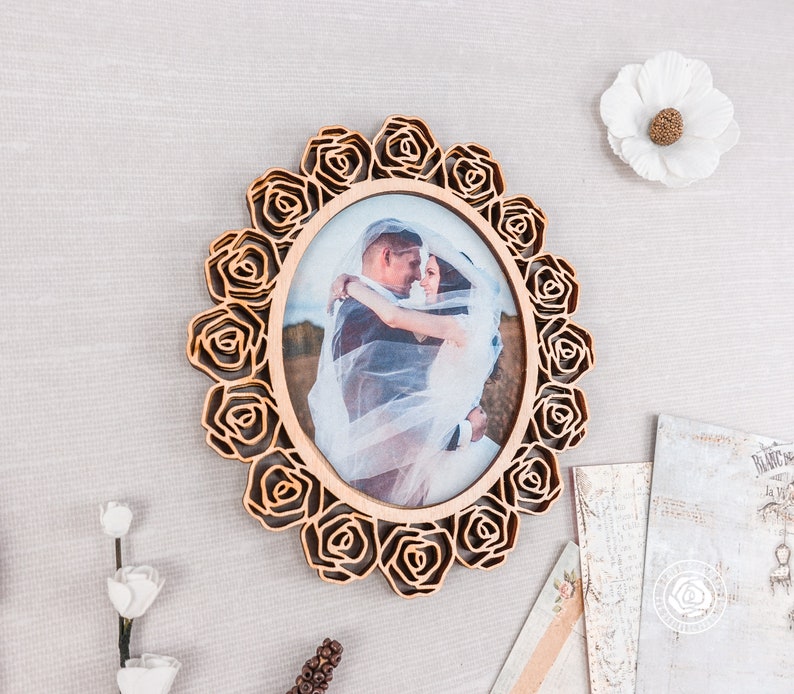 May include: A wooden photo frame with a rose design, featuring a wedding photo of a couple in a white dress and a suit.