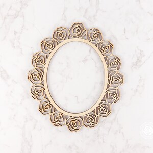 May include: A wooden frame with a decorative rose design. The frame is oval shaped and has a natural wood finish.