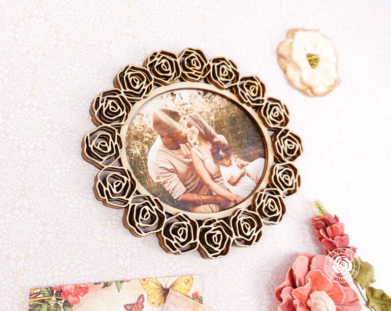 May include: A wooden photo frame with a decorative rose design. The frame holds a photo of a family of three.