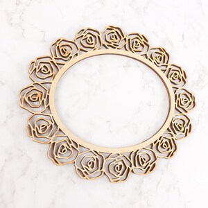 May include: A wooden frame with a circular cutout and a decorative design of roses around the edge.