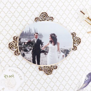 May include: A wooden oval photo frame with a carved rose design. The frame holds a photo of a couple in a forest setting. The photo shows a man and a woman holding hands and smiling.