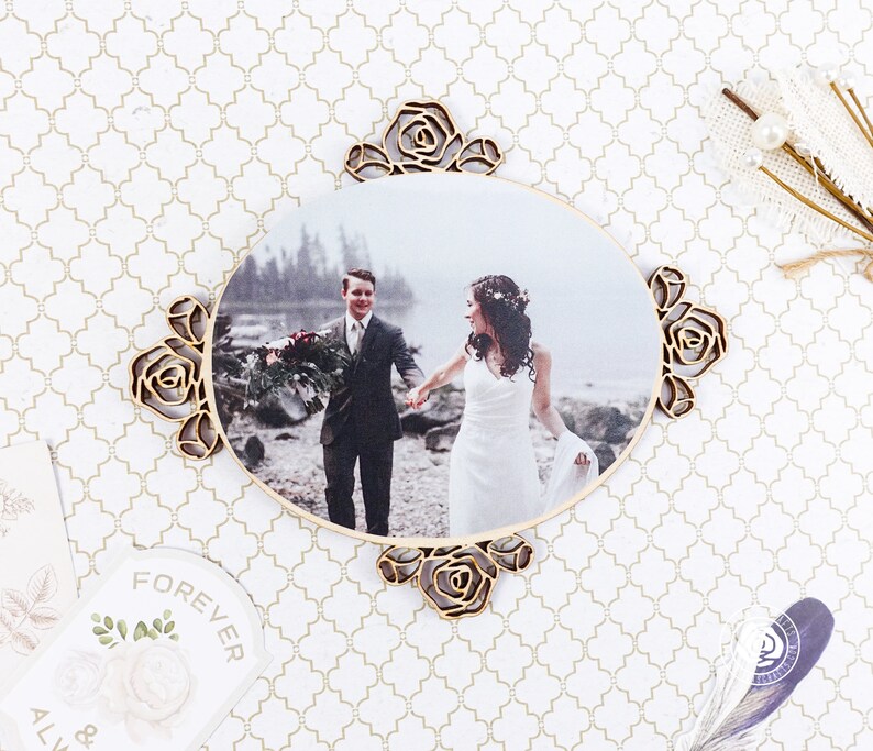 May include: A wooden oval photo frame with a carved rose design. The frame holds a photo of a couple in a forest setting. The photo shows a man and a woman holding hands and smiling.