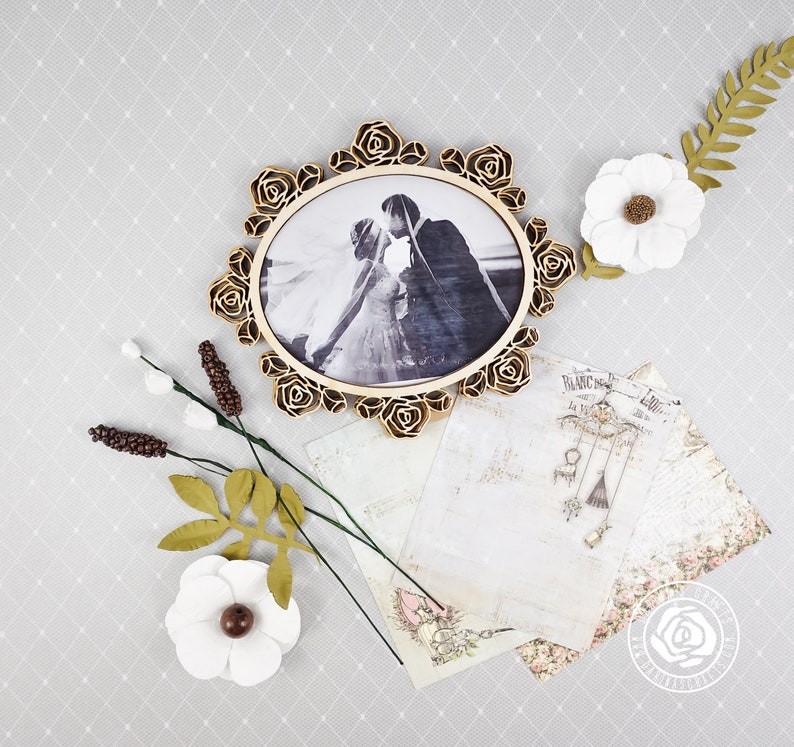 Puede incluir: Un marco de madera de color dorado con un dise&ntilde;o floral en relieve rodea una fotograf&iacute;a en blanco y negro de una pareja. El marco est&aacute; sobre un fondo blanco con un patr&oacute;n floral.