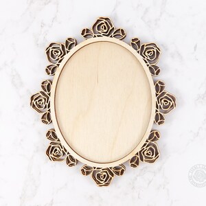 Puede incluir: Un marco ovalado de madera con un dise&ntilde;o decorativo de rosas. El marco est&aacute; hecho de madera clara y tiene un acabado natural.