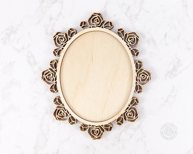 Puede incluir: Un marco ovalado de madera con un dise&ntilde;o decorativo de rosas. El marco est&aacute; hecho de madera clara y tiene un acabado natural.