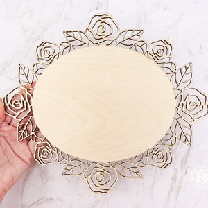 May include: A wooden oval-shaped plaque with a decorative rose design around the edge. The plaque is made of light wood and has a natural finish.