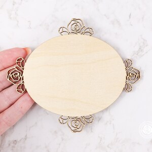 May include: A wooden oval sign with a decorative floral border. The sign is blank and ready to be personalized.