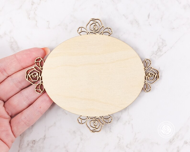 May include: A wooden oval sign with a decorative floral border. The sign is blank and ready to be personalized.