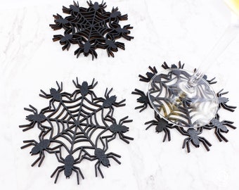 Pode incluir: Conjunto de três  tapetes de mesa pretos de teia de aranha com um design de aranha. Os tapetes de mesa são feitos de madeira e são perfeitos para proteger seus móveis de derramamentos.