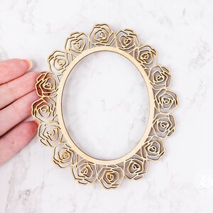 May include: A wooden frame with a decorative design of roses around the edge. The frame is unfinished and ready to be painted or stained.