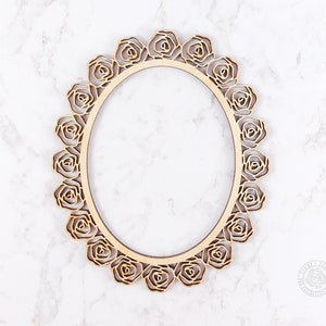May include: A wooden oval frame with a decorative rose design. The frame is made of light brown wood and has a smooth finish.