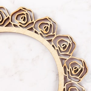 May include: A wooden frame with a decorative rose design. The frame is unfinished and has a natural wood color.