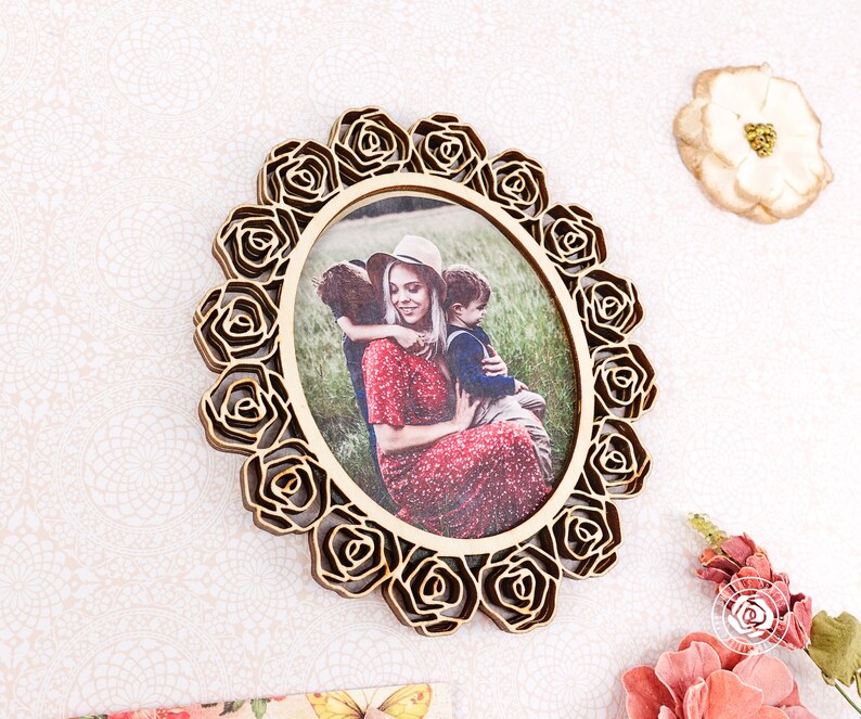 May include: A wooden photo frame with a decorative rose design. The frame is oval shaped and has a photo of a woman and two children inside.