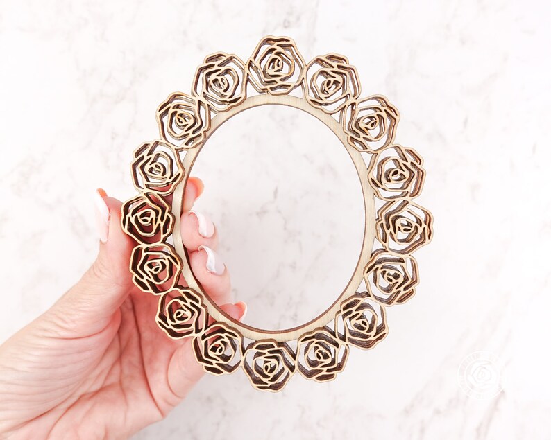 May include: A wooden frame with a circular design featuring a repeating pattern of carved roses. The frame is unfinished and ready to be painted or stained.