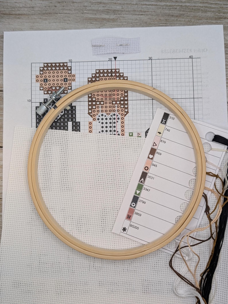 Peut inclure: Un kit de point de croix avec une toile Aida blanche, un cerceau &agrave; broder en bois, du fil &agrave; broder marron, noir et blanc, et un tableau de couleurs avec les num&eacute;ros de fil DMC.