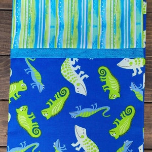 May include: Blue fabric with a repeating pattern of green and white chameleons. The fabric has a blue and white striped border.