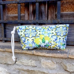 Puede incluir: Una bolsa de cremallera azul y amarilla con estampado de limón y un asa de cuerda blanca.