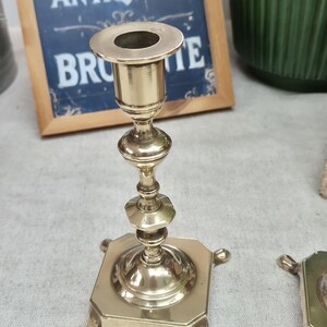 Peut inclure: Un bougeoir en laiton poli dot&eacute; d'une tige centrale avec des anneaux tourn&eacute;s d&eacute;coratifs et une base carr&eacute;e soutenue par quatre petits pieds incurv&eacute;s. Le haut du bougeoir pr&eacute;sente une ouverture circulaire con&ccedil;ue pour une bougie effil&eacute;e.