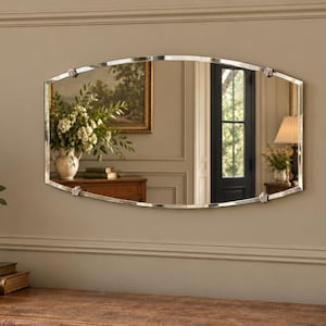 May include: An oval-shaped wall mirror with a thin, polished silver-toned metal frame. The mirror features four decorative, small metal accents positioned at the top, bottom, and sides, providing a structured border for the reflective glass surface.