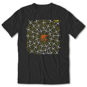 Peut inclure: T-shirt noir avec un motif de toile d'araignée. La toile est jaune avec des accents blancs et un centre rouge. Le texte "astronautes" est imprimé en jaune en haut à droite du t-shirt.