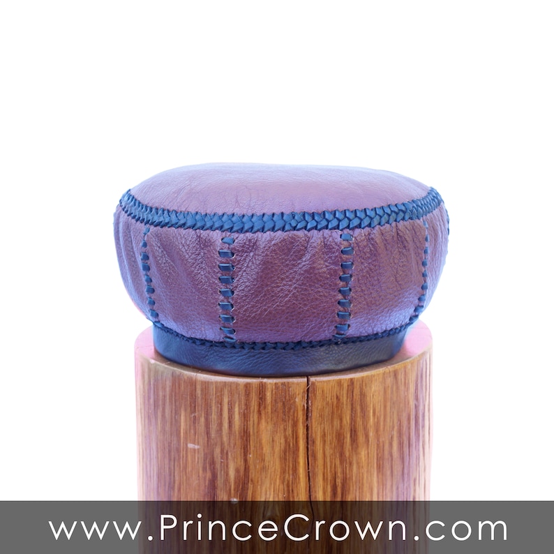 May include: A brown leather stool top with black stitching, sitting on a wooden base.