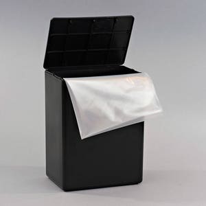 May include: A black rectangular trash can with a lid that is open. A white plastic bag is partially inside the can.