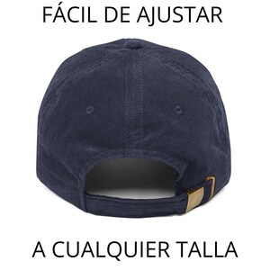 May include: Navy blue corduroy baseball cap with a curved brim and adjustable strap. The cap features a gold-colored metal buckle and the text "F&Aacute;CIL DE AJUSTAR A CUALQUIER TALLA".