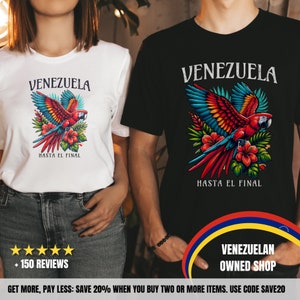 May include: Two t-shirts with a red, yellow, and blue parrot design. The parrot is flying over tropical flowers. The text on the shirts says "Venezuela" and "Hasta el final".