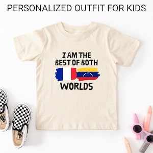 May include: Cream-colored t-shirt with the text "I AM THE BEST OF BOTH WORLDS" and a graphic of the French and Venezuelan flags. The shirt is part of a personalized outfit for kids. Checkered slip-on shoes and sunglasses are visible.