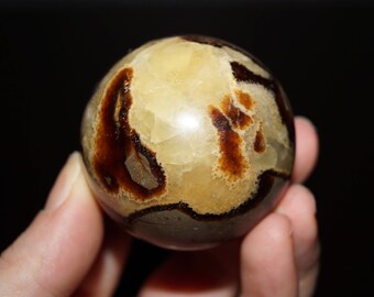 May include: A polished sphere of brown and beige crystal with a swirling pattern. The sphere is about 2 inches in diameter.
